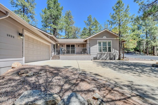 single story home featuring concrete driveway, covered porch, and an attached garage