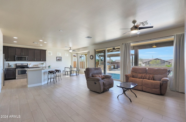 living room with light hardwood / wood-style floors, sink, and ceiling fan