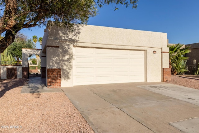 view of front of property with stucco siding, brick siding, concrete driveway, and an attached garage