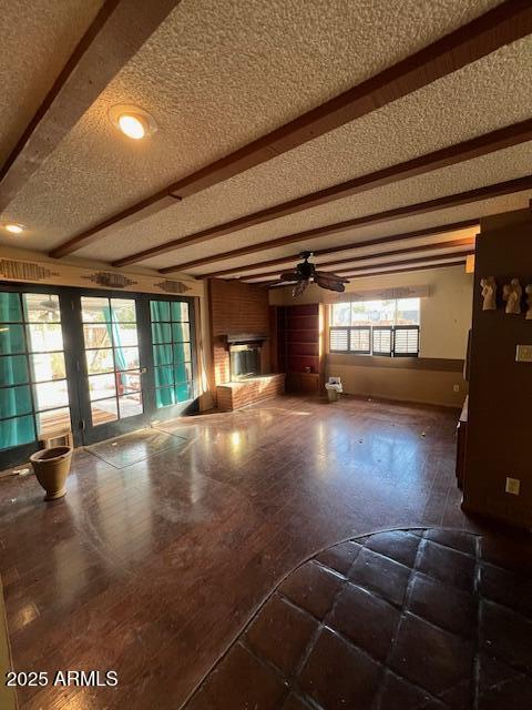 unfurnished living room with beamed ceiling, ceiling fan, and a textured ceiling