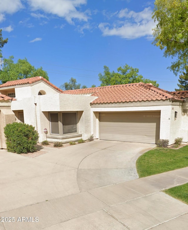 mediterranean / spanish home with a garage, stucco siding, driveway, and a tile roof