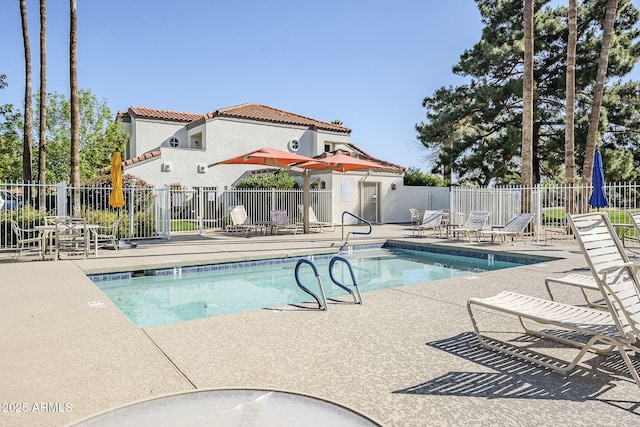 community pool with a patio area and fence