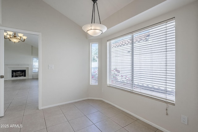 empty room featuring baseboards, light tile patterned flooring, a fireplace, and vaulted ceiling