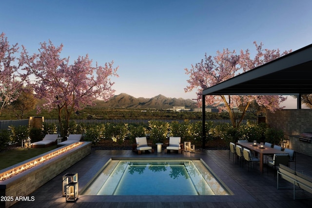 19355 N 73rd Way Unit E-2015, Scottsdale, AZ 85255 - pool at dusk with a fenced backyard, a mountain view, a patio area, and outdoor dining space