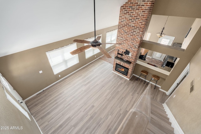 20818 N 21st Dr, Phoenix, AZ 85027 - unfurnished living room featuring a high ceiling, a brick fireplace, a ceiling fan, baseboards, and wood finished floors