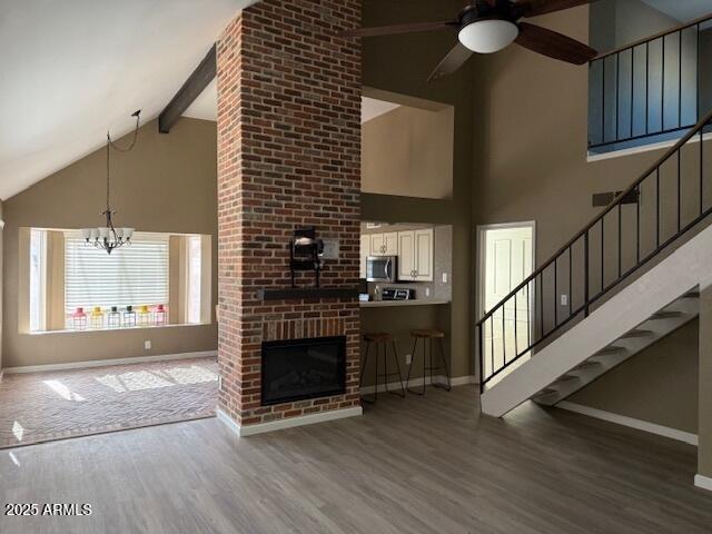20818 N 21st Dr, Phoenix, AZ 85027 - unfurnished living room featuring baseboards, ceiling fan with notable chandelier, wood finished floors, and high vaulted ceiling