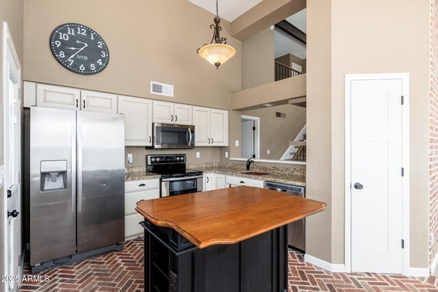 20818 N 21st Dr, Phoenix, AZ 85027 - kitchen with white cabinets, a high ceiling, appliances with stainless steel finishes, brick floor, and visible vents