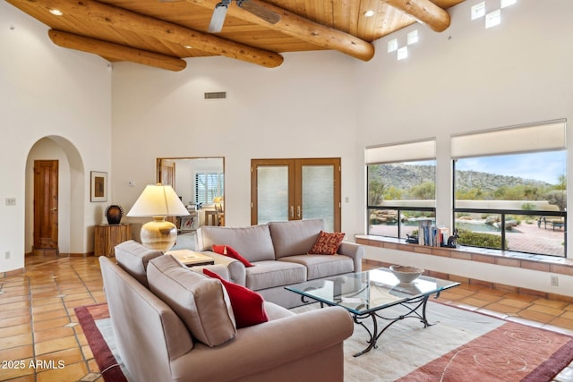 living area featuring light tile patterned floors, visible vents, arched walkways, french doors, and wooden ceiling