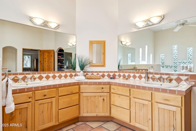 full bathroom featuring a sink, decorative backsplash, ceiling fan, and double vanity