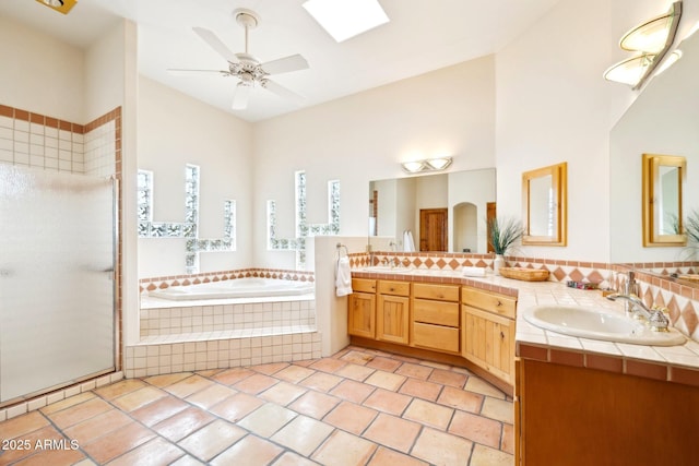 bathroom featuring a garden tub, double vanity, a stall shower, and a sink