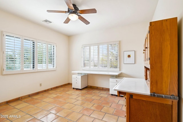 unfurnished office with light tile patterned floors, visible vents, baseboards, and a ceiling fan