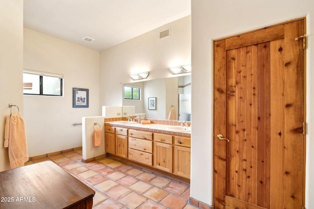 bathroom with a sink, visible vents, double vanity, and tile patterned floors