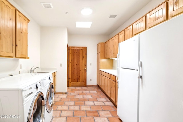 clothes washing area with a sink, baseboards, visible vents, and washing machine and clothes dryer