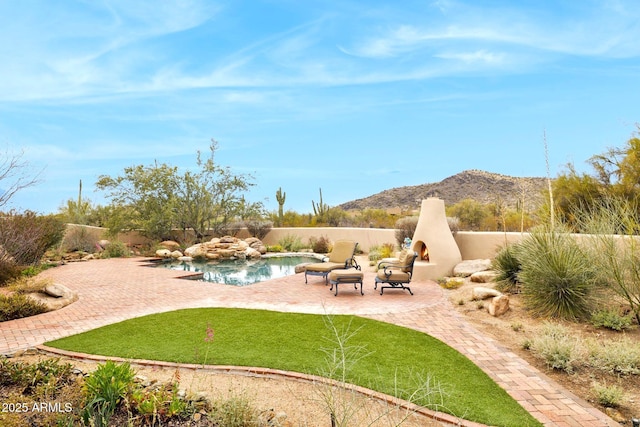 view of yard featuring a patio, fence, a mountain view, a lit fireplace, and a fenced in pool