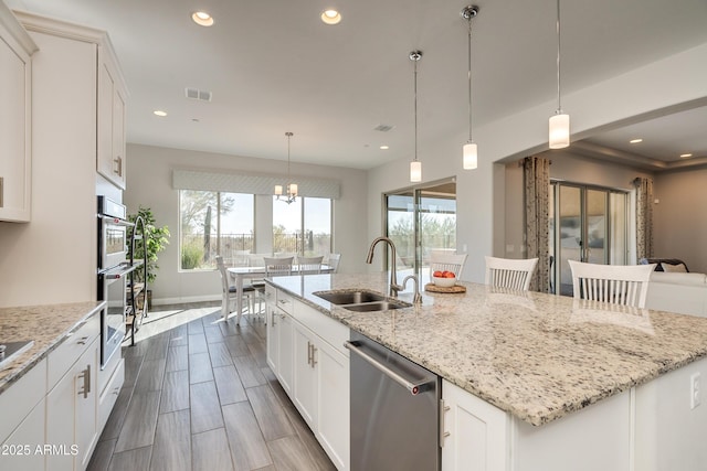 kitchen featuring white cabinetry, stainless steel dishwasher, and an island with sink