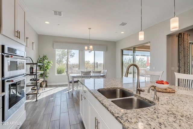 kitchen featuring light stone countertops, sink, a wealth of natural light, and white cabinets