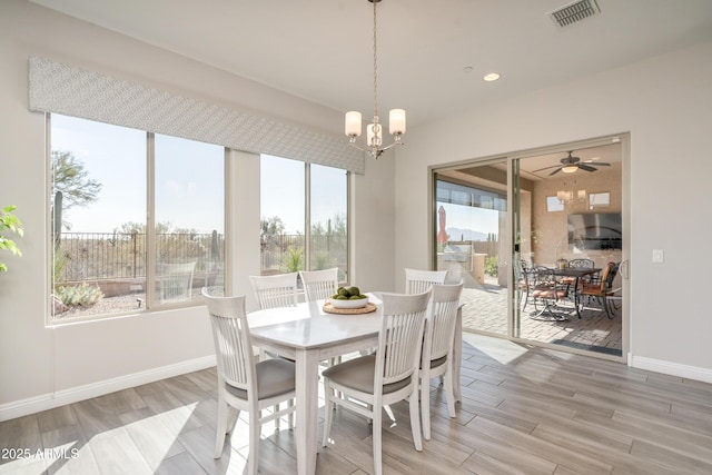 dining space featuring wood-type flooring and ceiling fan with notable chandelier