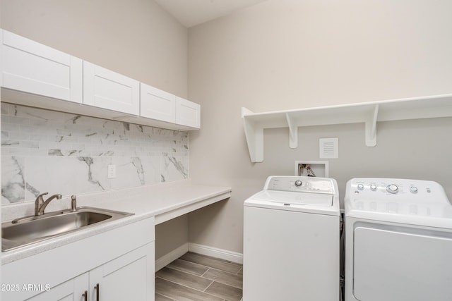 clothes washing area with cabinets, washer and clothes dryer, and sink