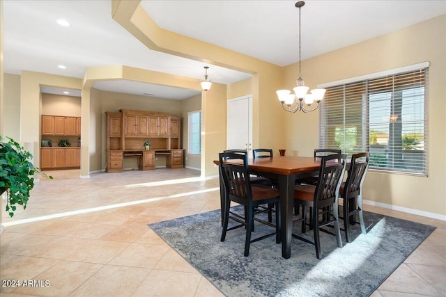 dining room featuring a wealth of natural light, light tile patterned floors, a notable chandelier, and built in desk