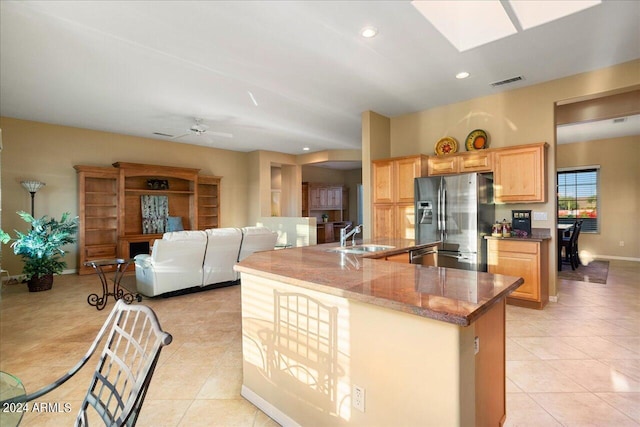 kitchen featuring sink, light brown cabinetry, light tile patterned floors, and stainless steel fridge