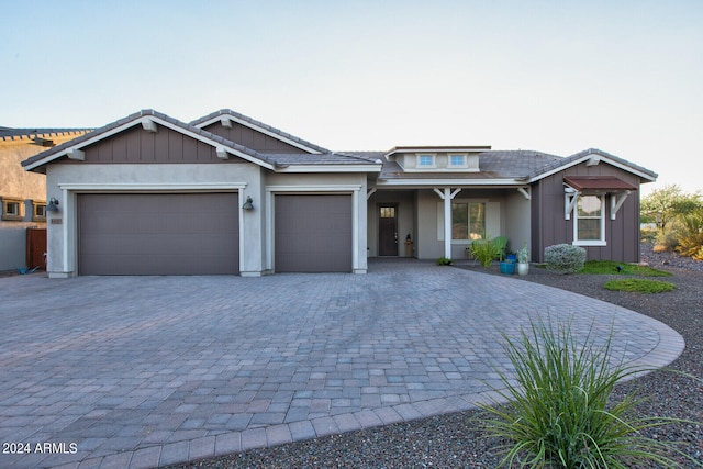 view of front of property featuring a garage, decorative driveway, a tiled roof, and stucco siding