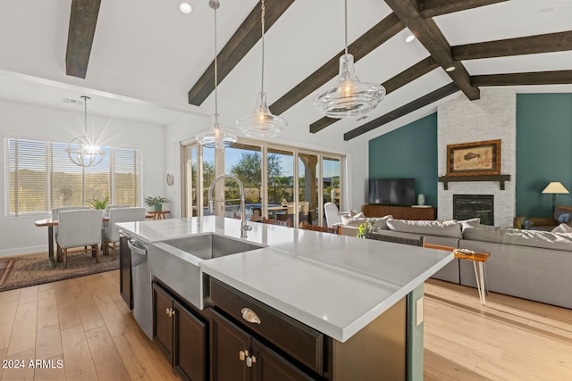 kitchen with light hardwood / wood-style floors, dishwasher, an island with sink, and decorative light fixtures