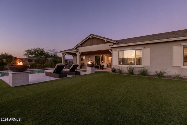 back house at dusk with a patio, an outdoor living space with a fire pit, and a yard