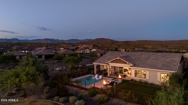 back house at dusk featuring a fenced in pool, a mountain view, and a patio area