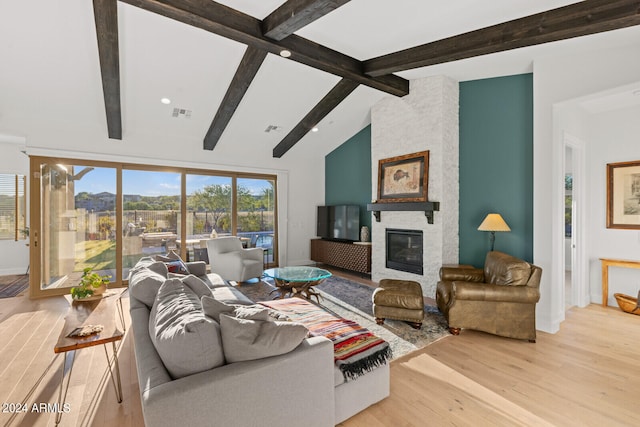 living room featuring light wood-type flooring, a fireplace, and lofted ceiling with beams