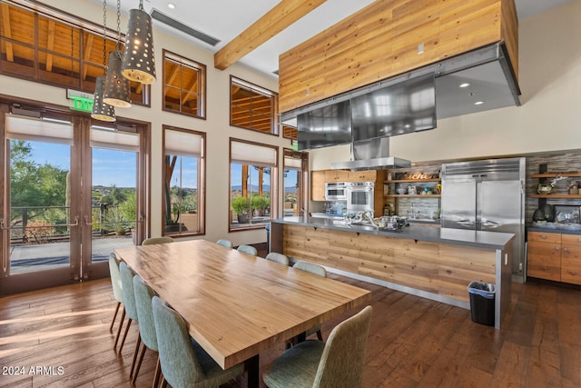 dining area with beam ceiling, dark hardwood / wood-style floors, and a towering ceiling