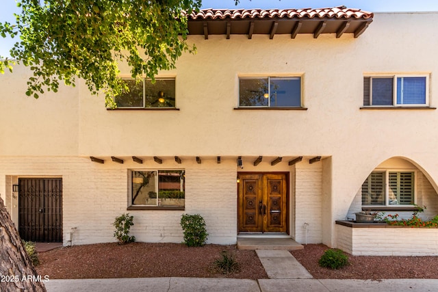 view of front of property with french doors, a tile roof, and stucco siding