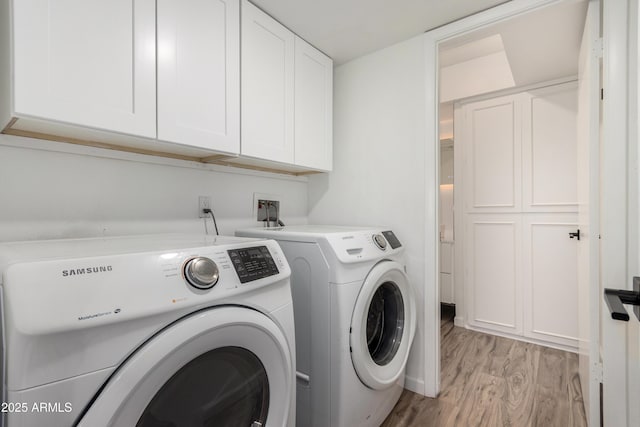 laundry area featuring separate washer and dryer, cabinet space, and light wood finished floors