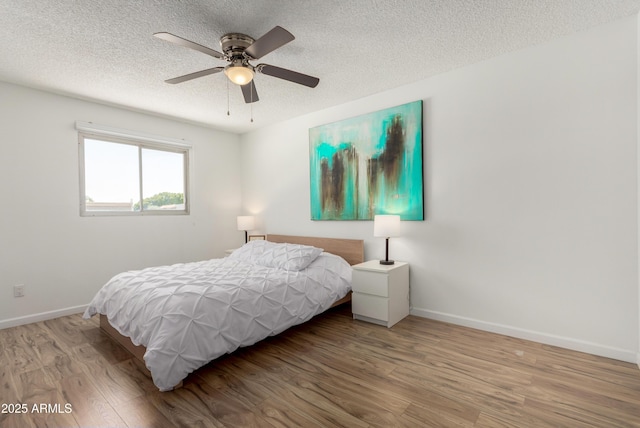 bedroom featuring baseboards, a textured ceiling, ceiling fan, and wood finished floors