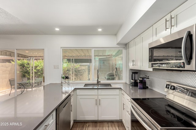 kitchen featuring backsplash, a sink, white cabinets, light wood-style floors, and stainless steel appliances