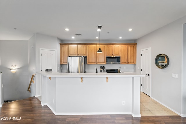 kitchen with light wood-type flooring, stainless steel appliances, a spacious island, and a kitchen bar