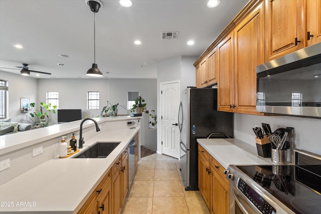 kitchen with light tile patterned flooring, sink, decorative light fixtures, ceiling fan, and stainless steel appliances