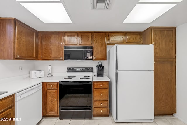 kitchen with visible vents, brown cabinetry, and white appliances