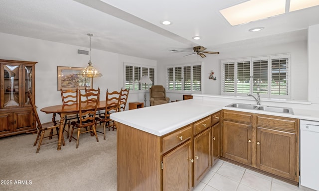 kitchen featuring visible vents, light countertops, a sink, white dishwasher, and brown cabinets