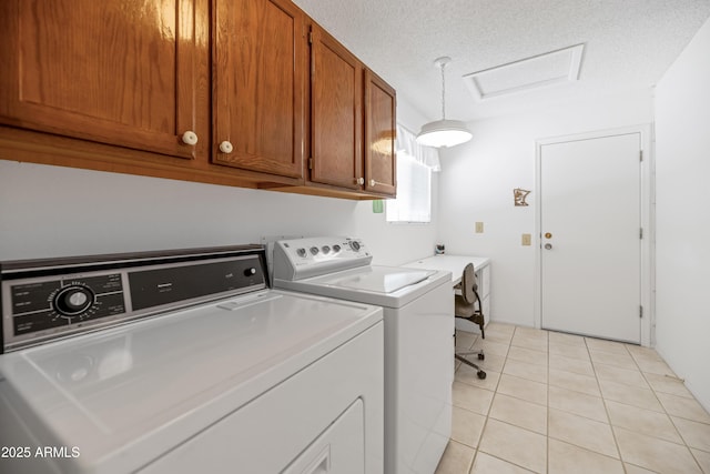 washroom with a textured ceiling, separate washer and dryer, light tile patterned flooring, and cabinet space