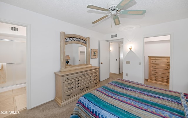 bedroom with a textured ceiling, ensuite bath, a ceiling fan, and visible vents