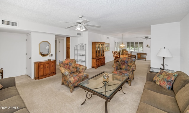 carpeted living room with visible vents, a textured ceiling, and ceiling fan