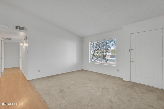 unfurnished living room with visible vents, light carpet, and a textured ceiling