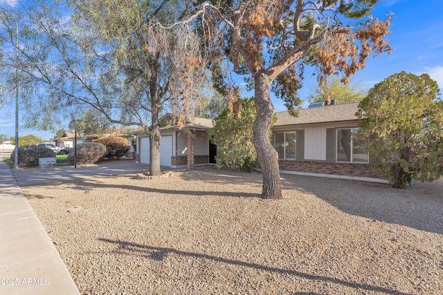 ranch-style home with brick siding, concrete driveway, a garage, and roof with shingles