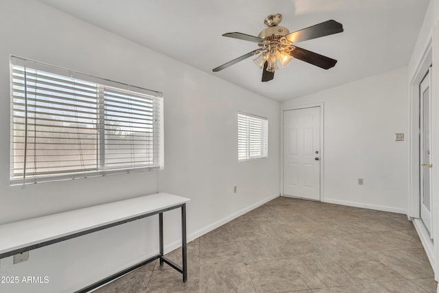 interior space with baseboards, ceiling fan, and vaulted ceiling