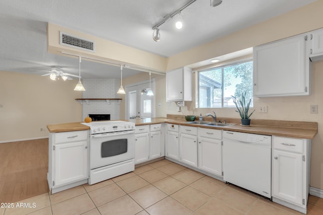 kitchen with white appliances, visible vents, a peninsula, a sink, and white cabinets