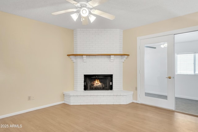 unfurnished living room featuring baseboards, a textured ceiling, wood finished floors, and a fireplace