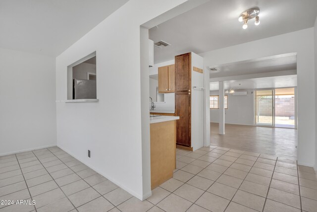 kitchen with light tile patterned flooring, refrigerator, sink, and a wall mounted air conditioner