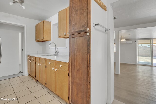 kitchen with light wood-type flooring, sink, and a wall mounted AC