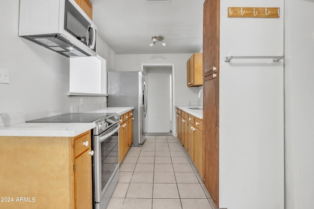 kitchen featuring light tile patterned flooring, sink, and stainless steel appliances