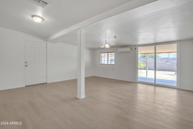 basement featuring light wood-type flooring and an AC wall unit